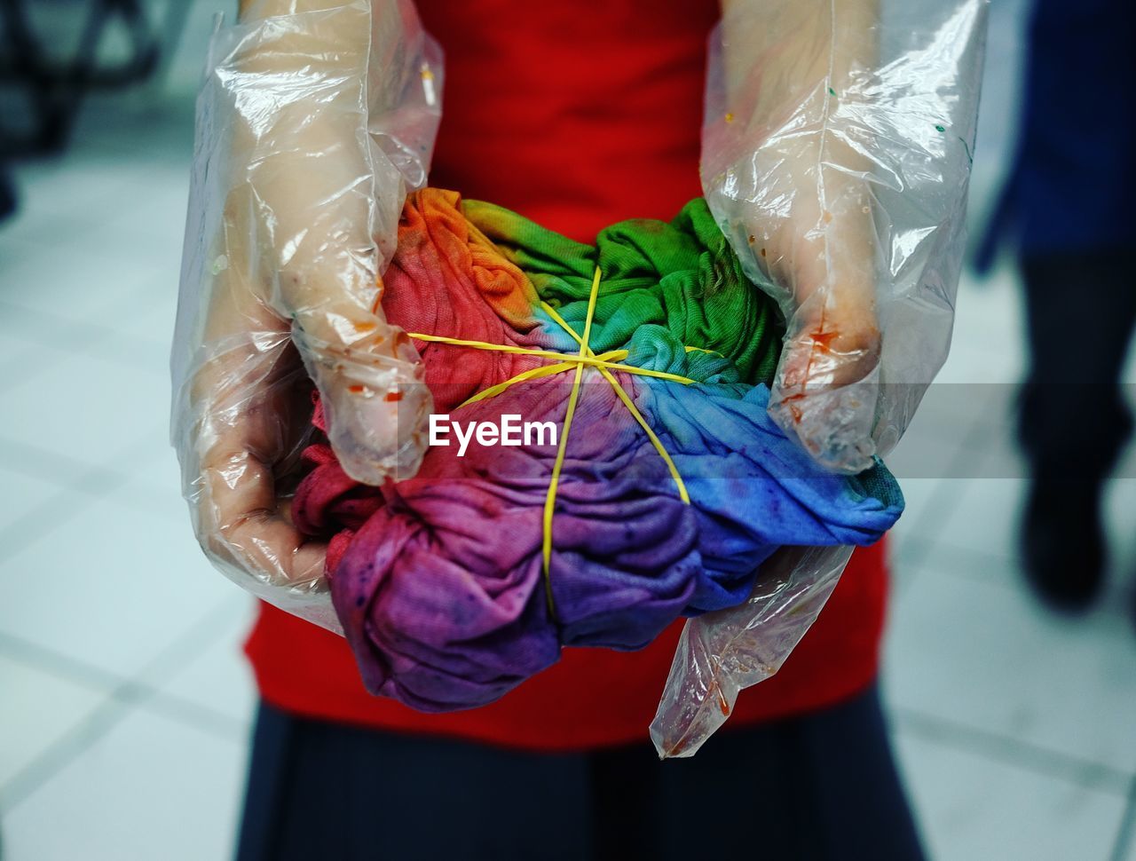 Midsection of person holding messy multi colored fabric