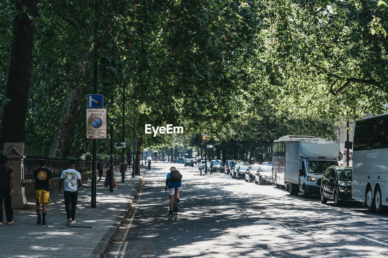 REAR VIEW OF PEOPLE WALKING ON STREET IN CITY