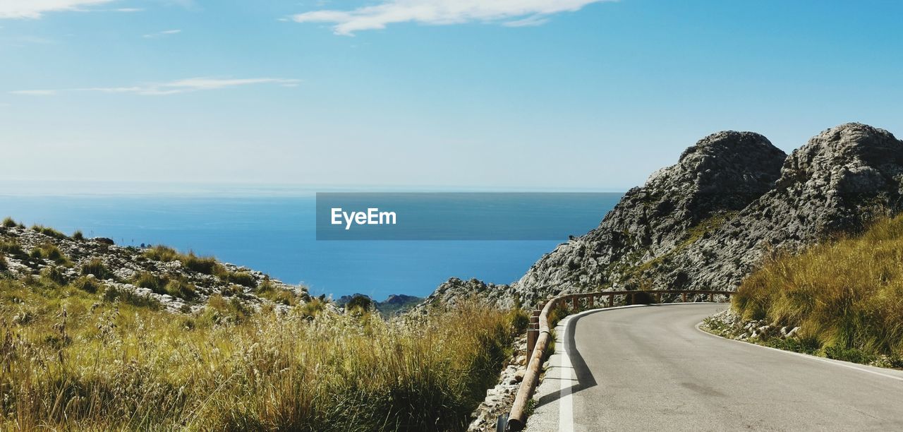 Scenic view of road by sea against sky