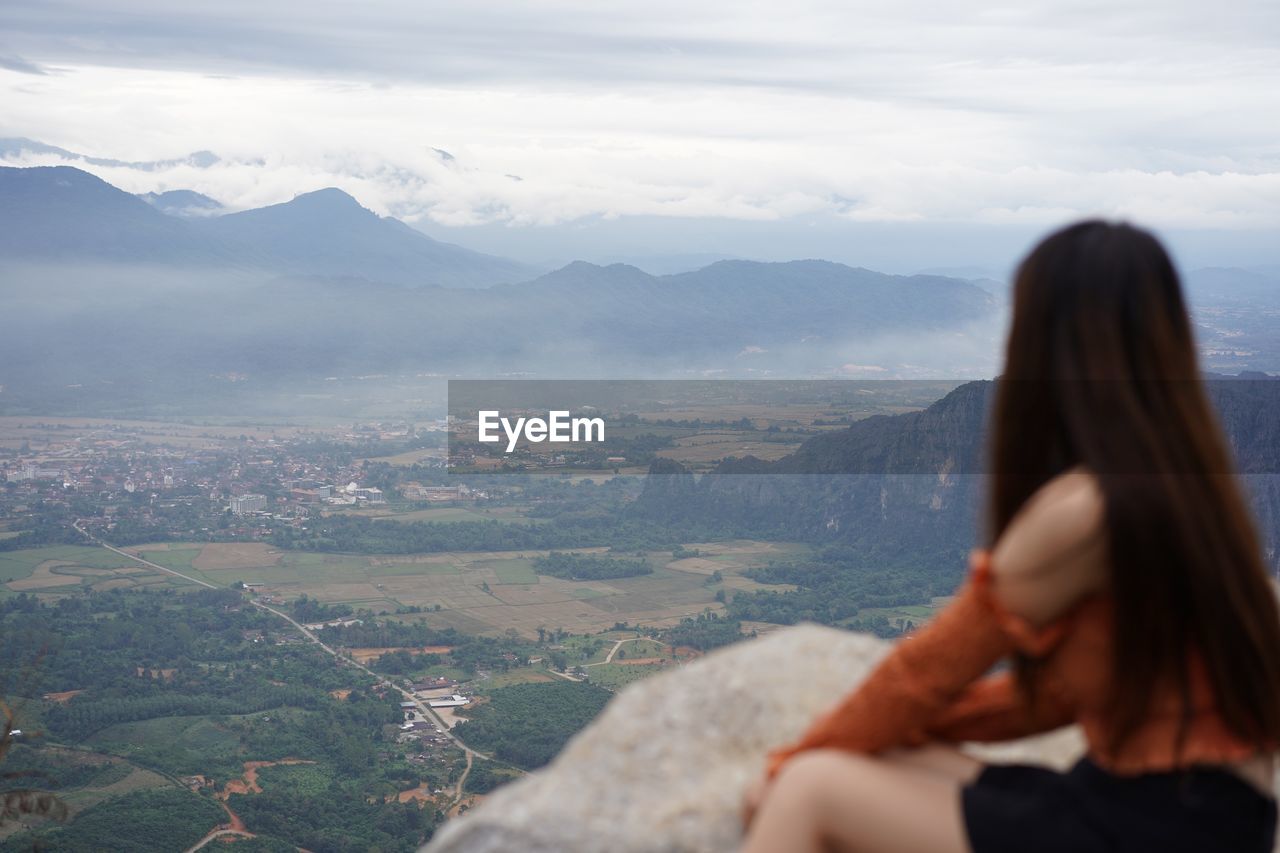 Rear view of woman looking at mountains against sky