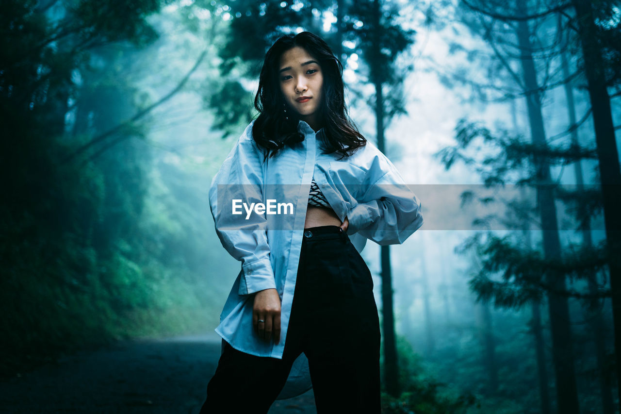 BEAUTIFUL YOUNG WOMAN STANDING IN FOREST