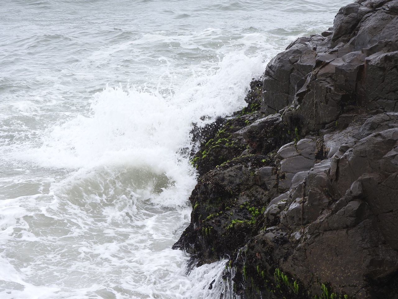 High angle view of wave splashing on rock formation in sea