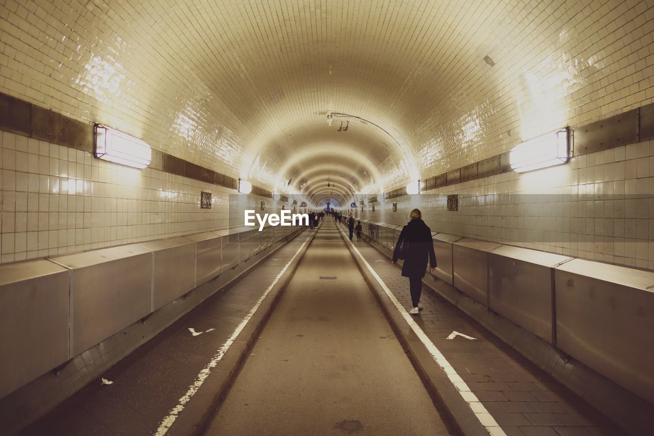 Rear view of woman walking in tunnel