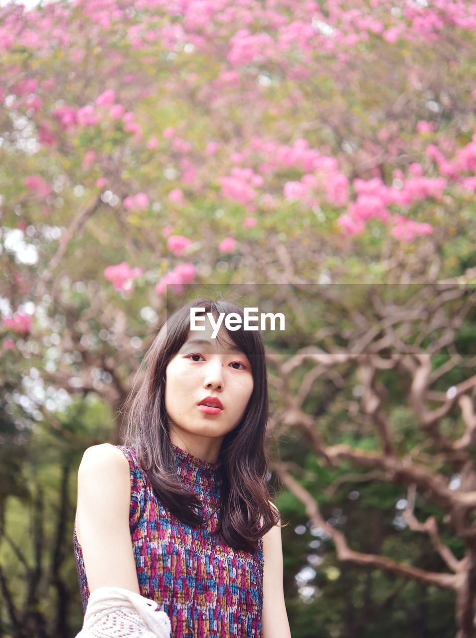 Portrait of beautiful young woman standing against plants