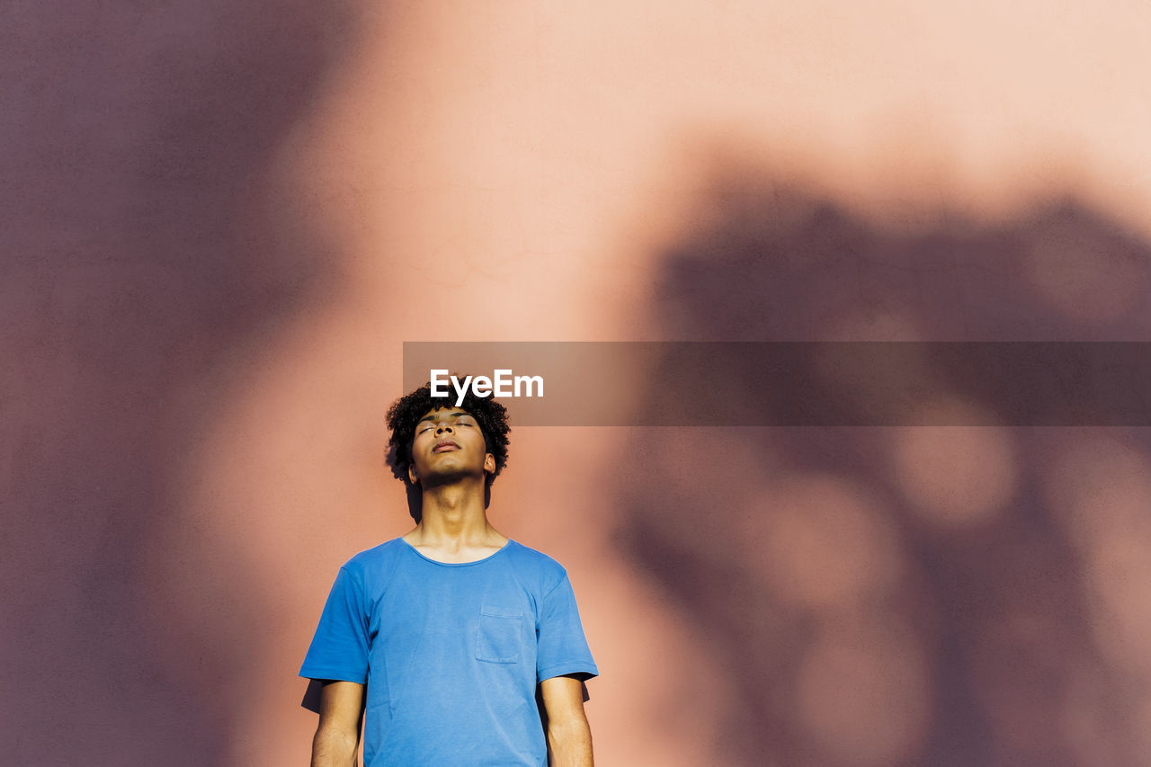 Man with eyes closed leaning on coral wall