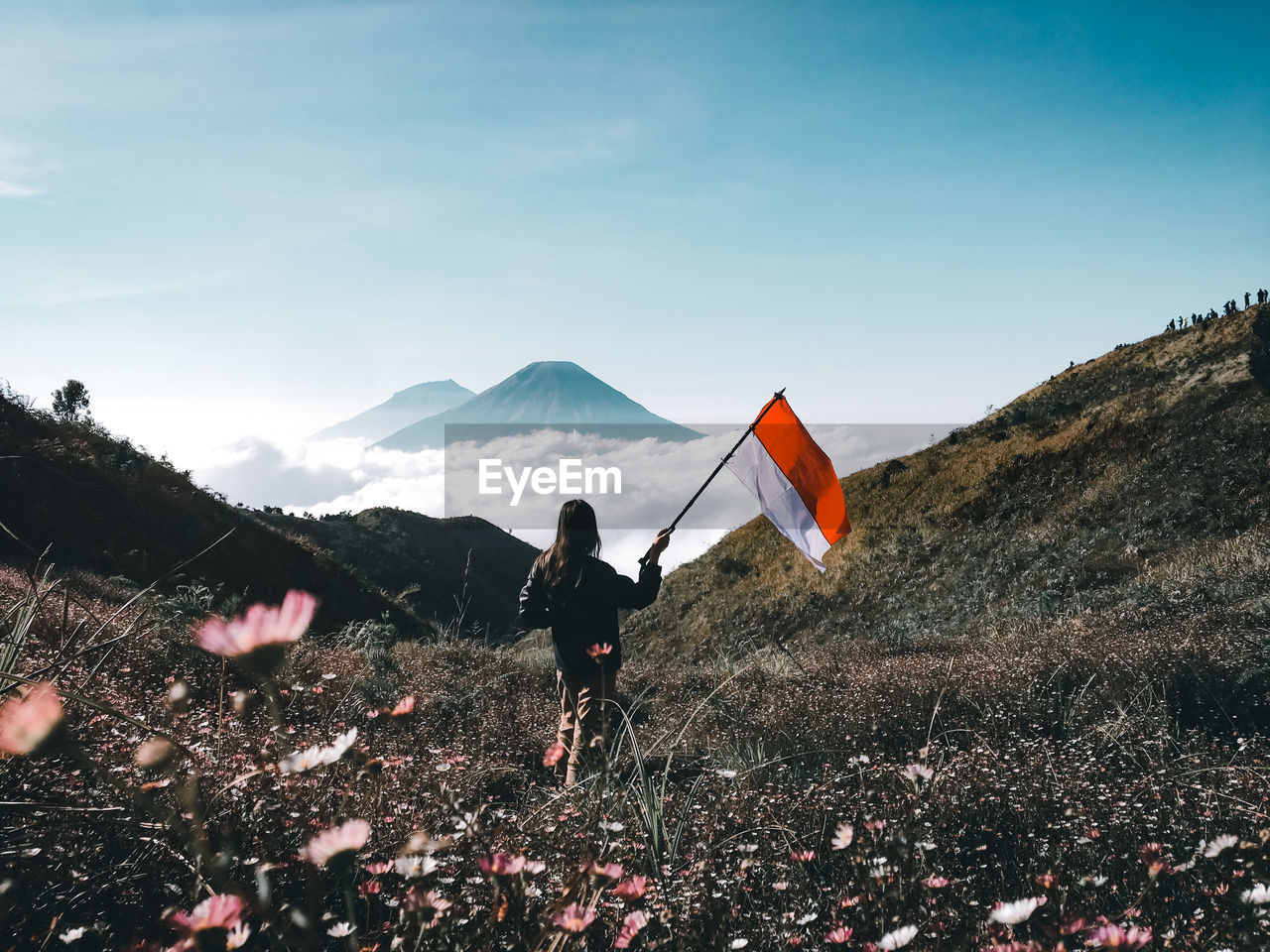 Woman standing with flag on field against mountains