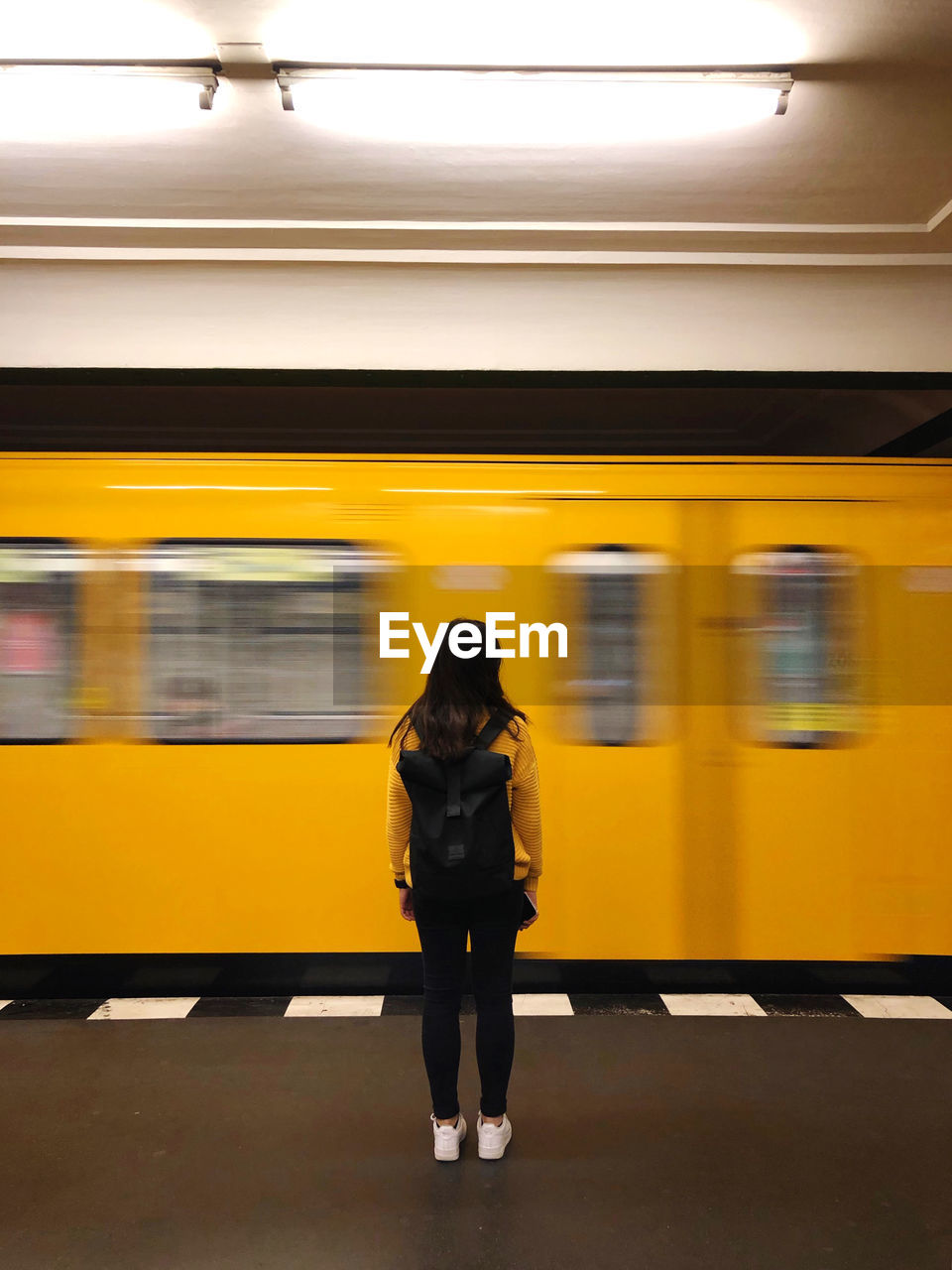 Rear view of woman standing against moving subway train