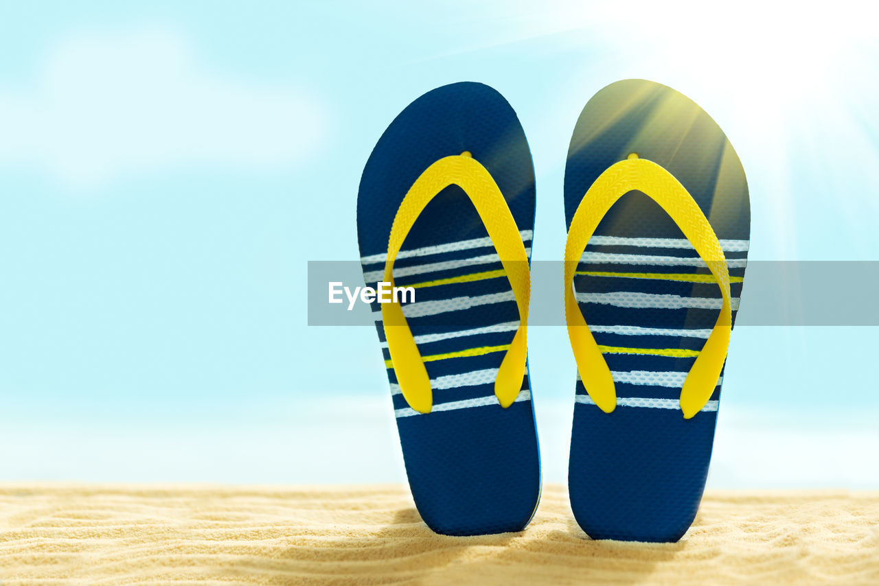 CLOSE-UP OF YELLOW SHOES ON BEACH