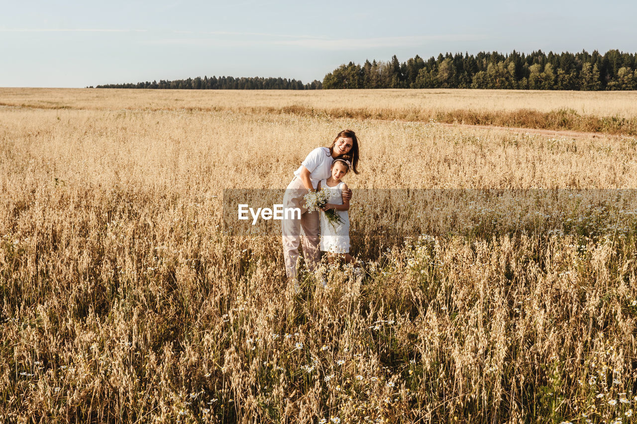 REAR VIEW OF PEOPLE ENJOYING IN FIELD