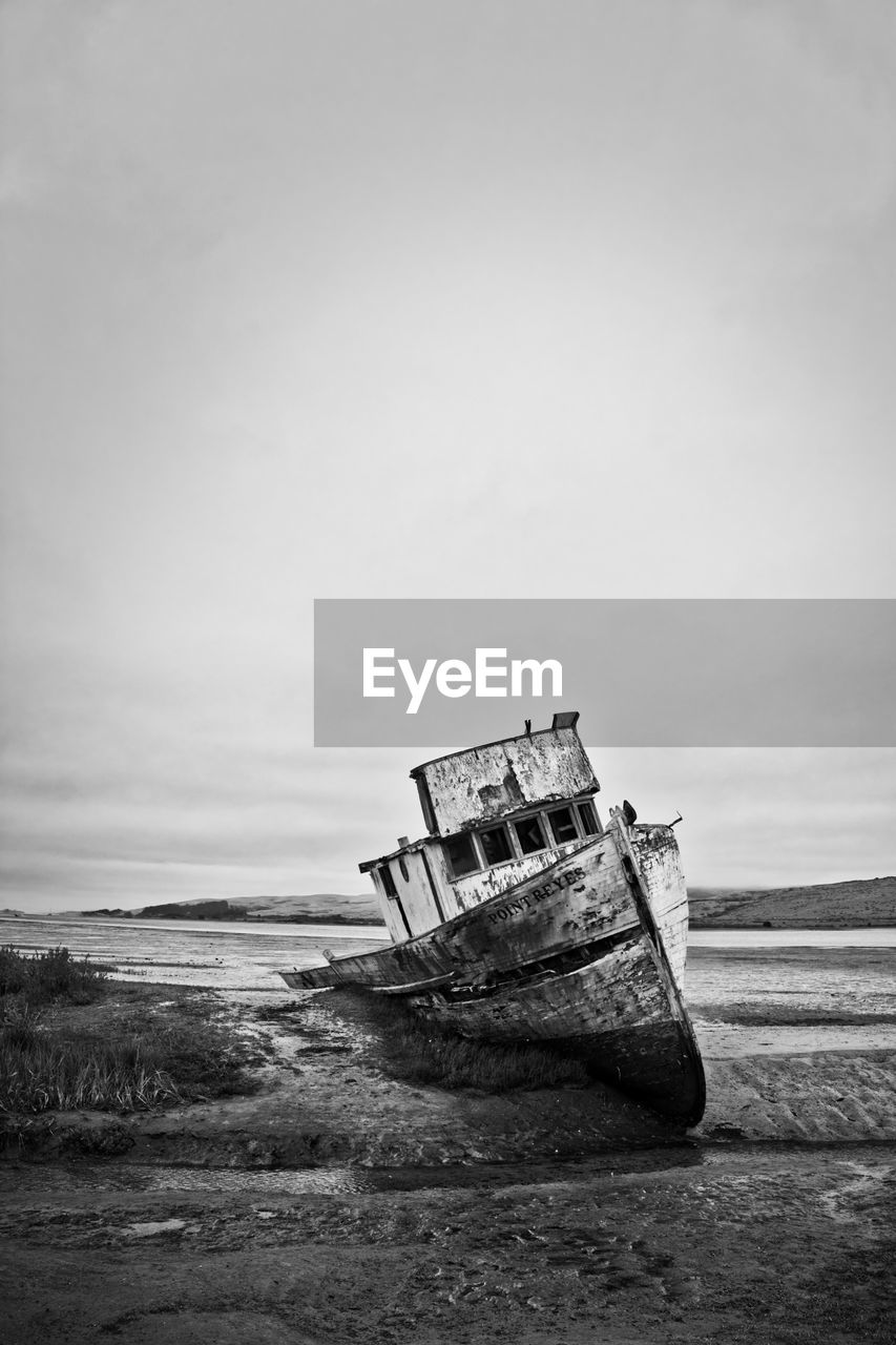 Abandoned boat on beach against sky