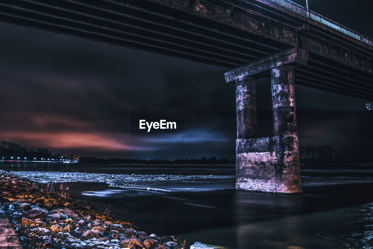 Low angle view of bridge over frozen river at night