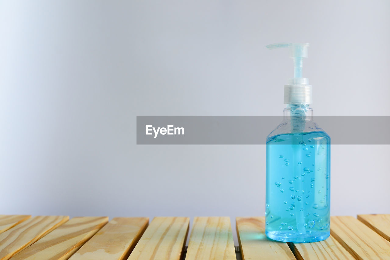 Close-up of blue bottle on table against white background