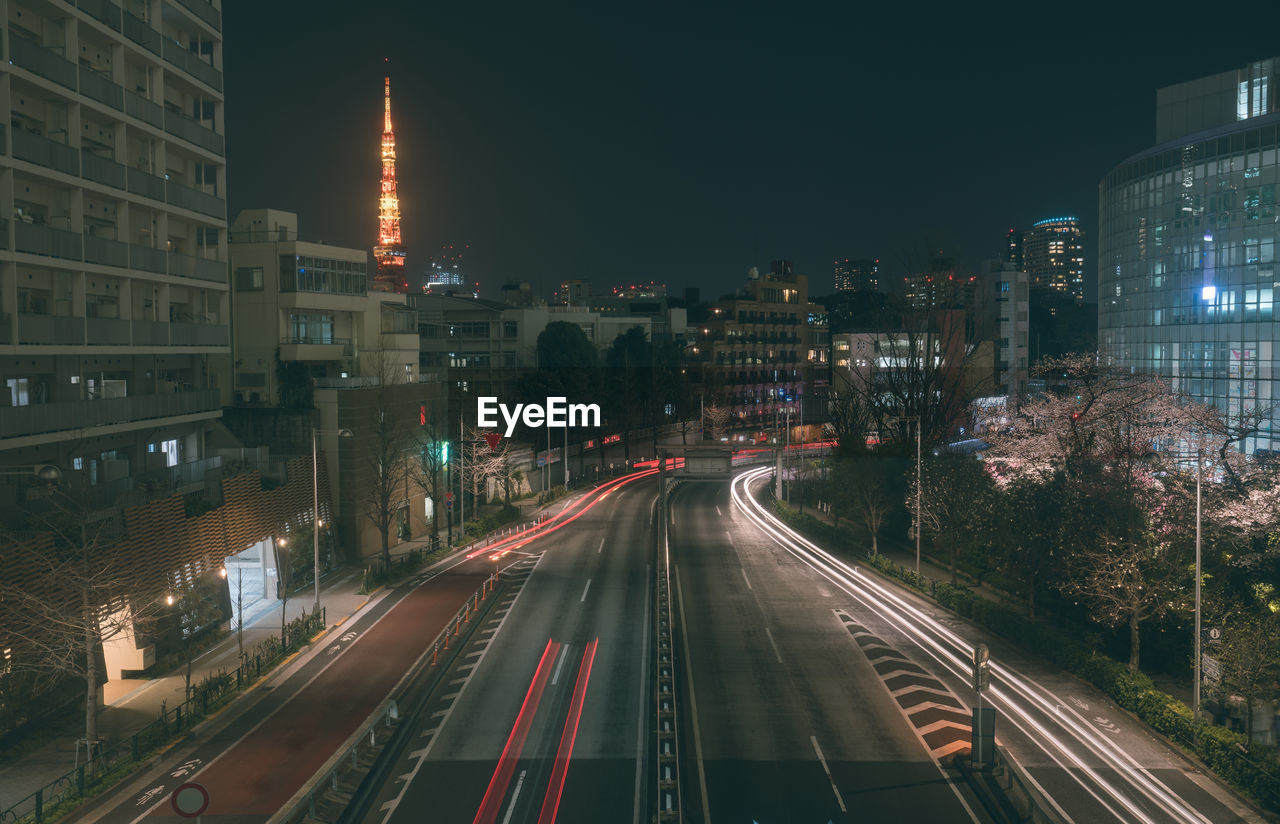 HIGH ANGLE VIEW OF LIGHT TRAILS ON STREET AMIDST BUILDINGS IN CITY