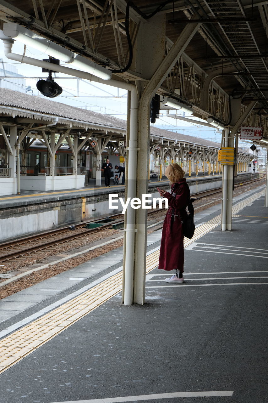 Rear view of woman standing at railroad station