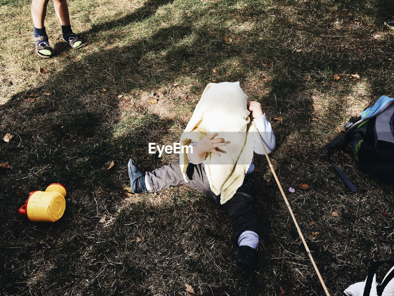 High angle view of boy covering face with towel while sitting on field