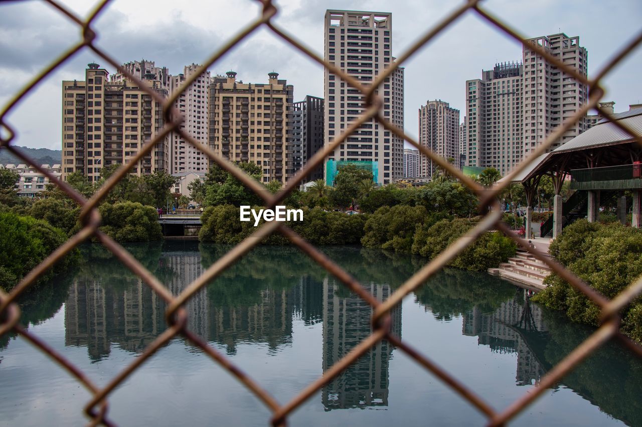 CHAINLINK FENCE BY BUILDINGS AGAINST SKY