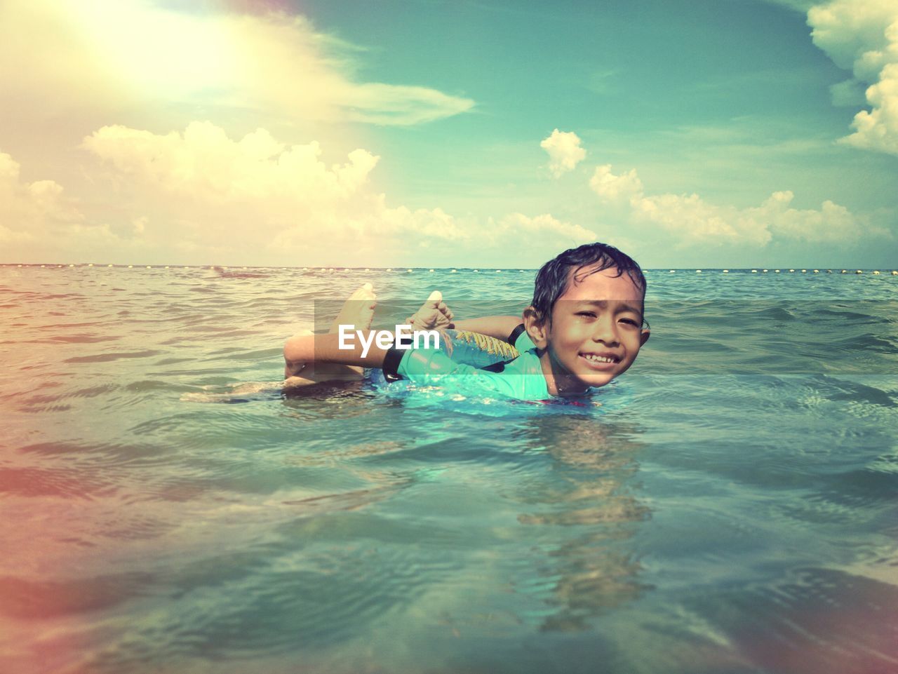 Portrait of boy swimming in sea against sky