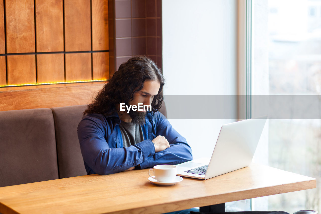 Young woman using mobile phone while sitting on table