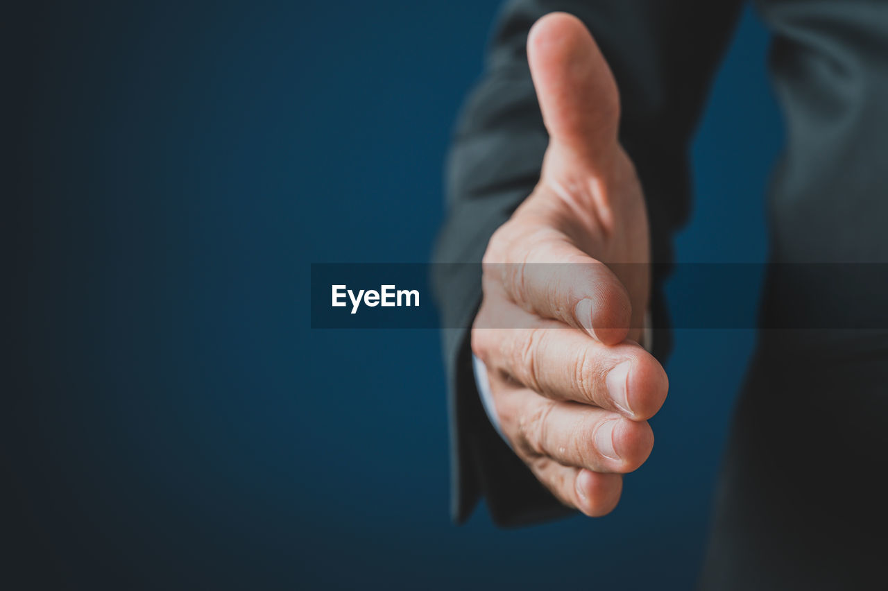 CLOSE-UP OF HUMAN HAND OVER BLUE BACKGROUND