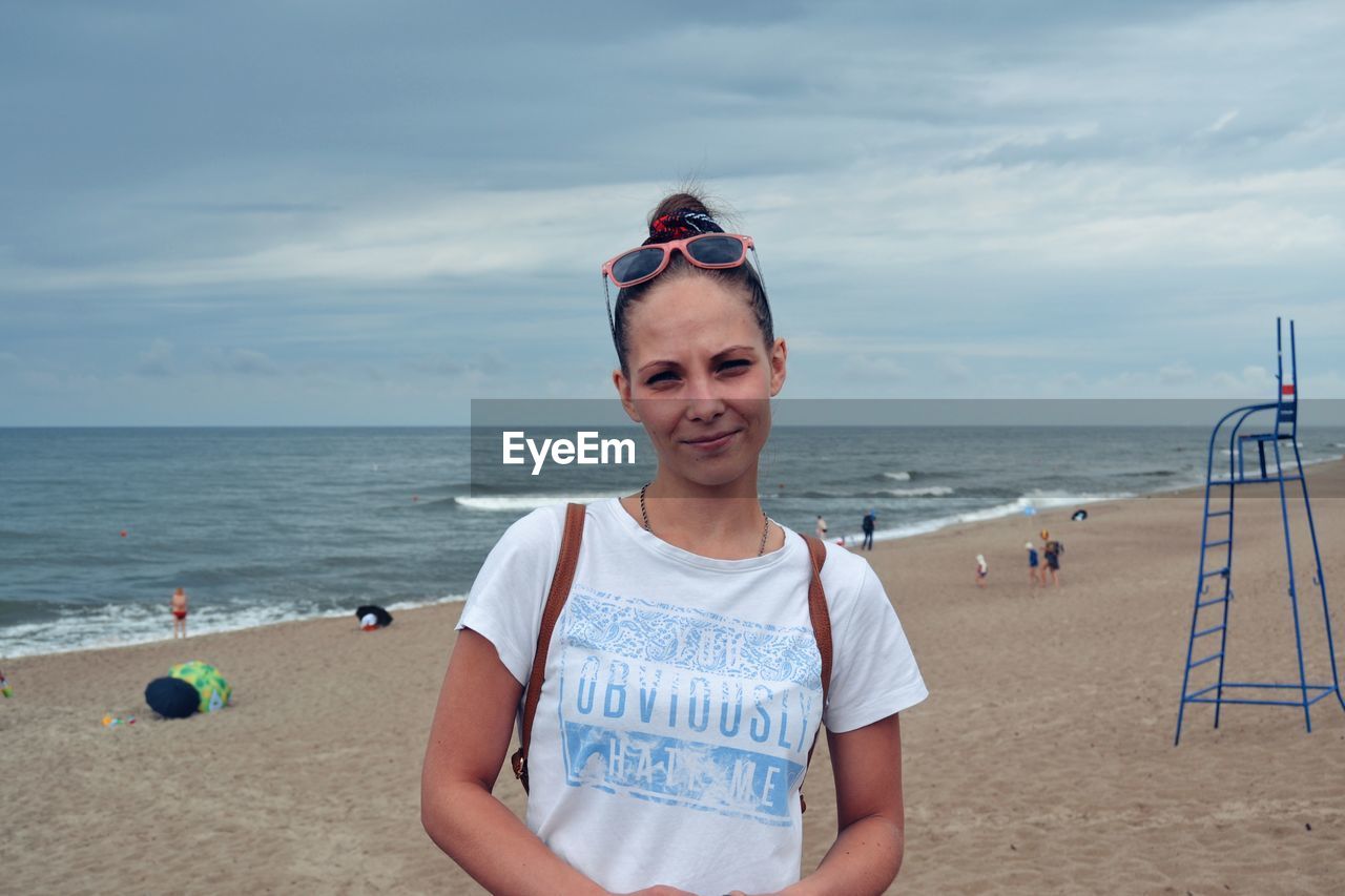 Portrait of woman standing at beach against sky