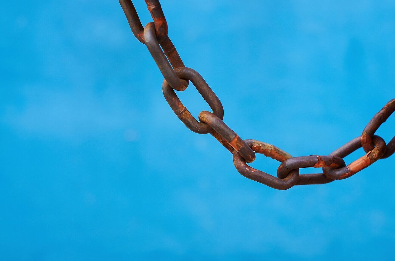 Low angle view of chain against clear blue sky