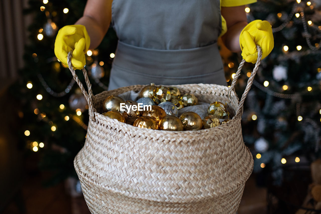 Preparing for christmas. basket with new year's decorations of gold color in hands. xmas atmosphere