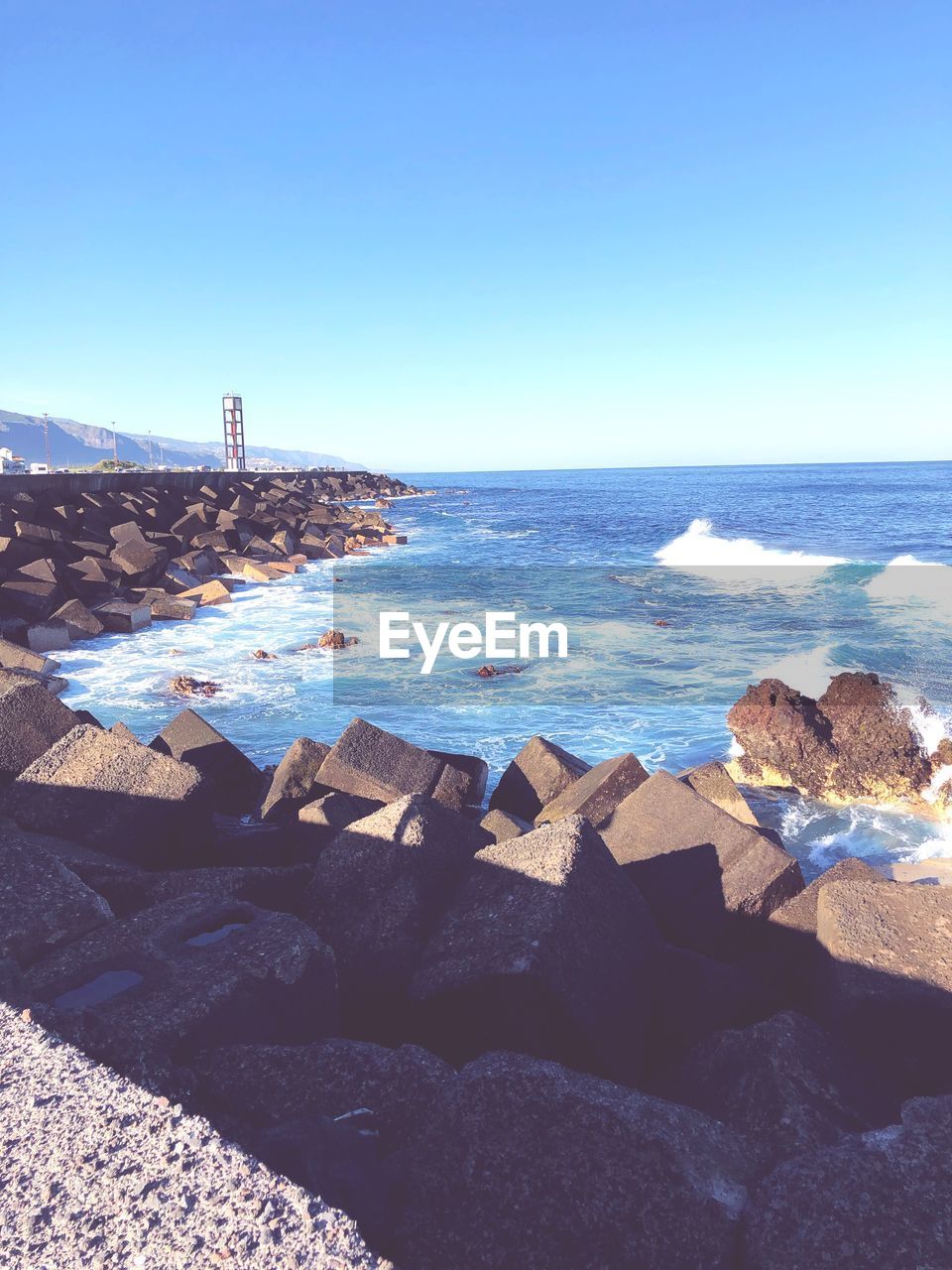 ROCKS ON BEACH AGAINST CLEAR BLUE SKY