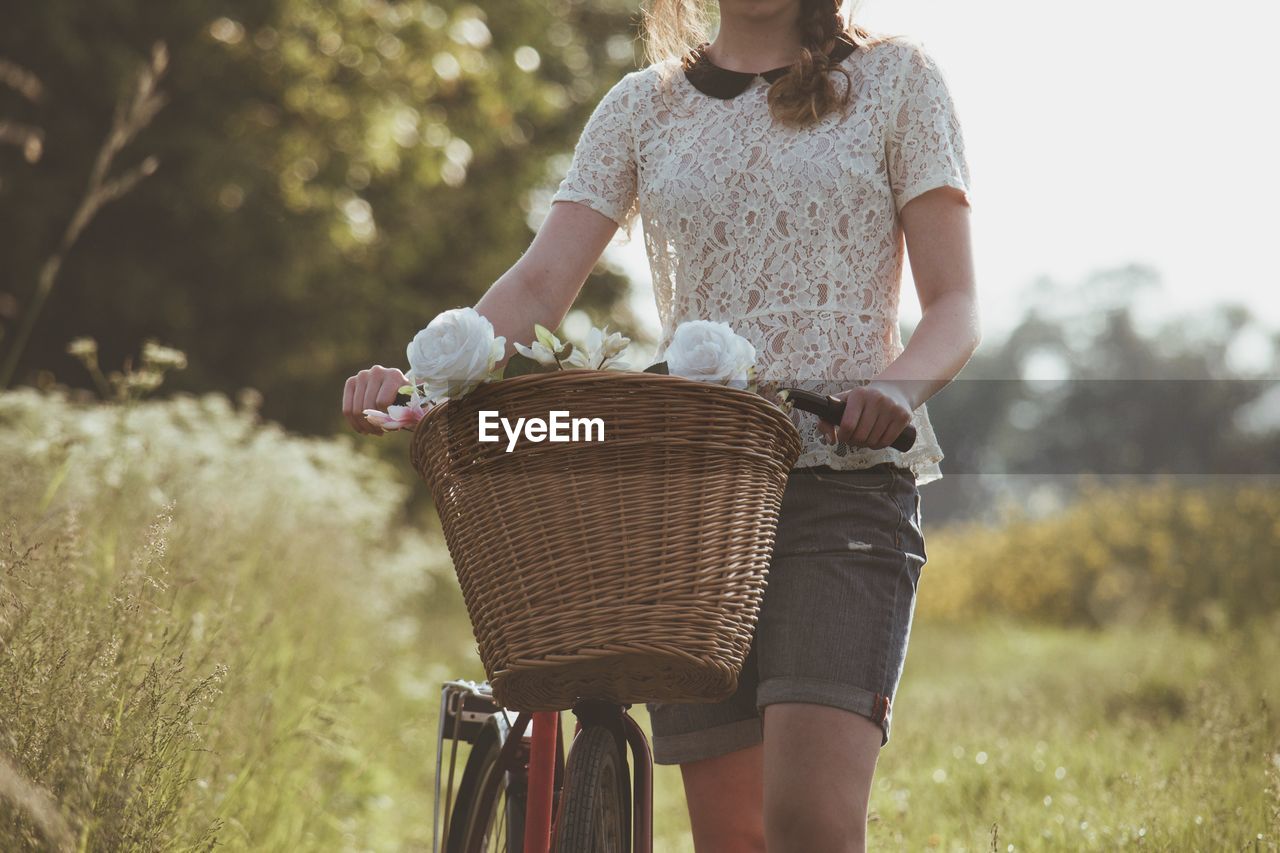 Mid section of a woman with bicycle on landscape