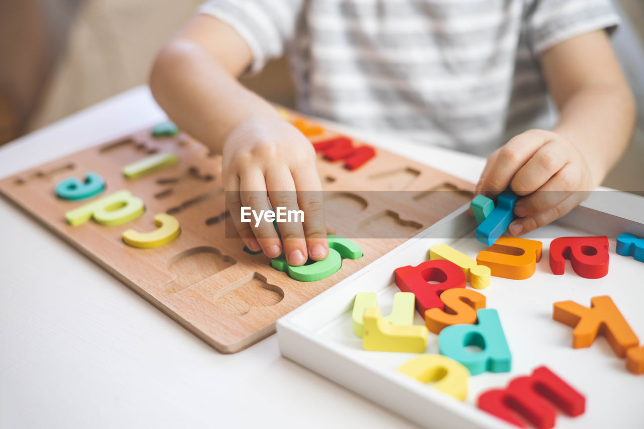 midsection of woman with toy blocks on table