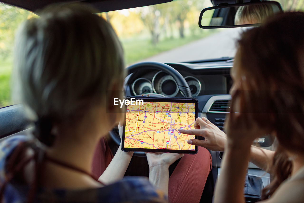 rear view of woman using mobile phone in car