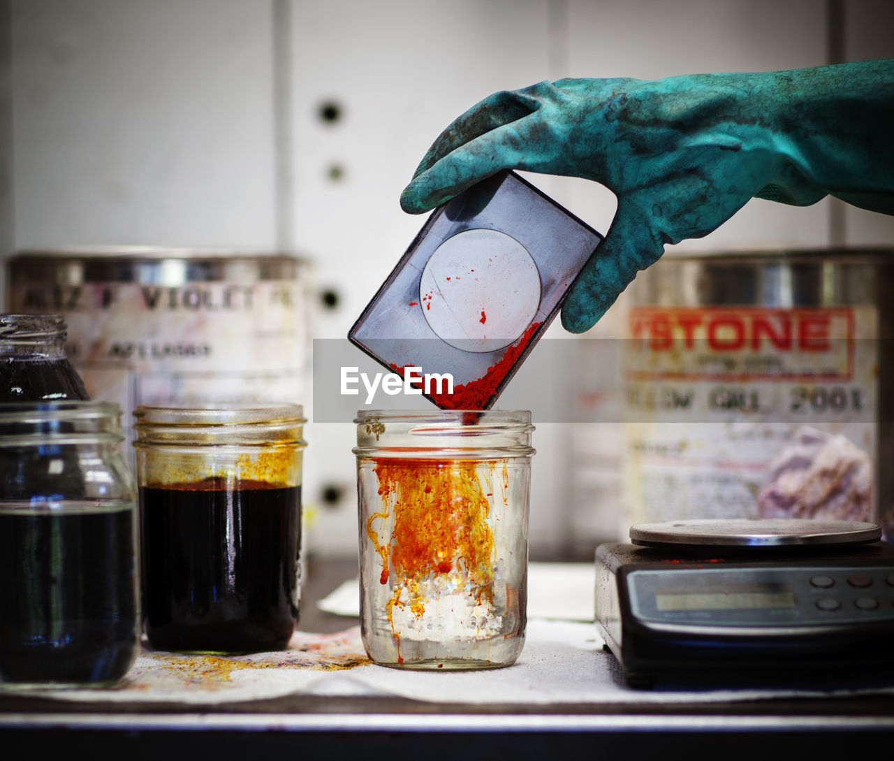 Cropped image of worker pouring dye in liquid at table in workshop