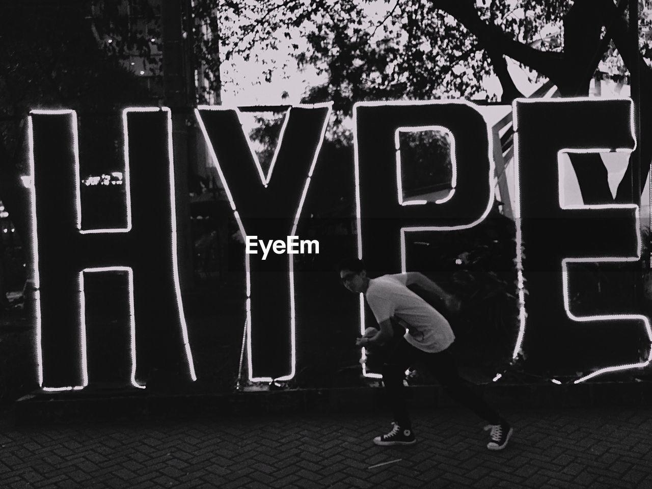 PEOPLE WALKING ON FOOTPATH IN FRONT OF TEXT ON WALL