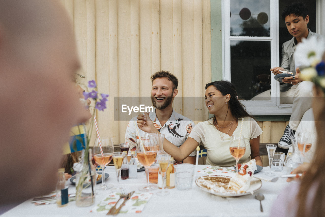 Man and woman enjoying with friends during dinner party while sitting at cafe table