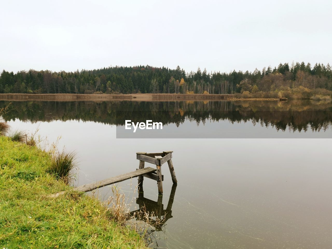 WOODEN POSTS ON LAKE AGAINST SKY