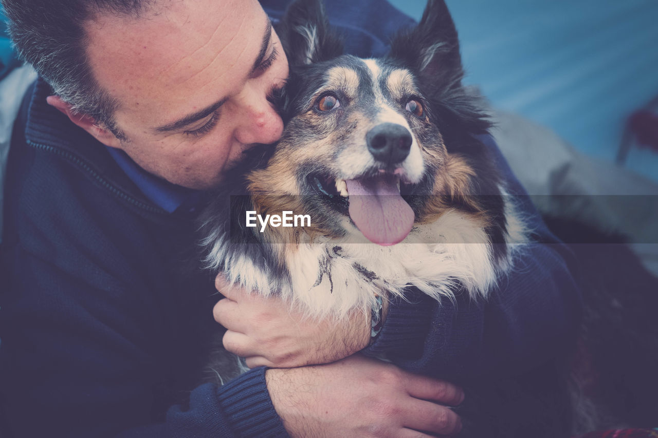 Close-up of man embracing dog in tent