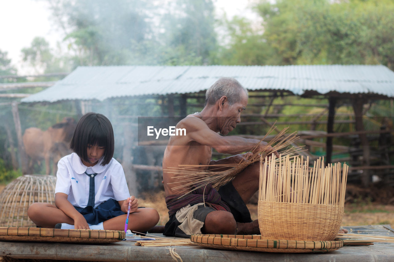 Grandfather by girl with basket on field