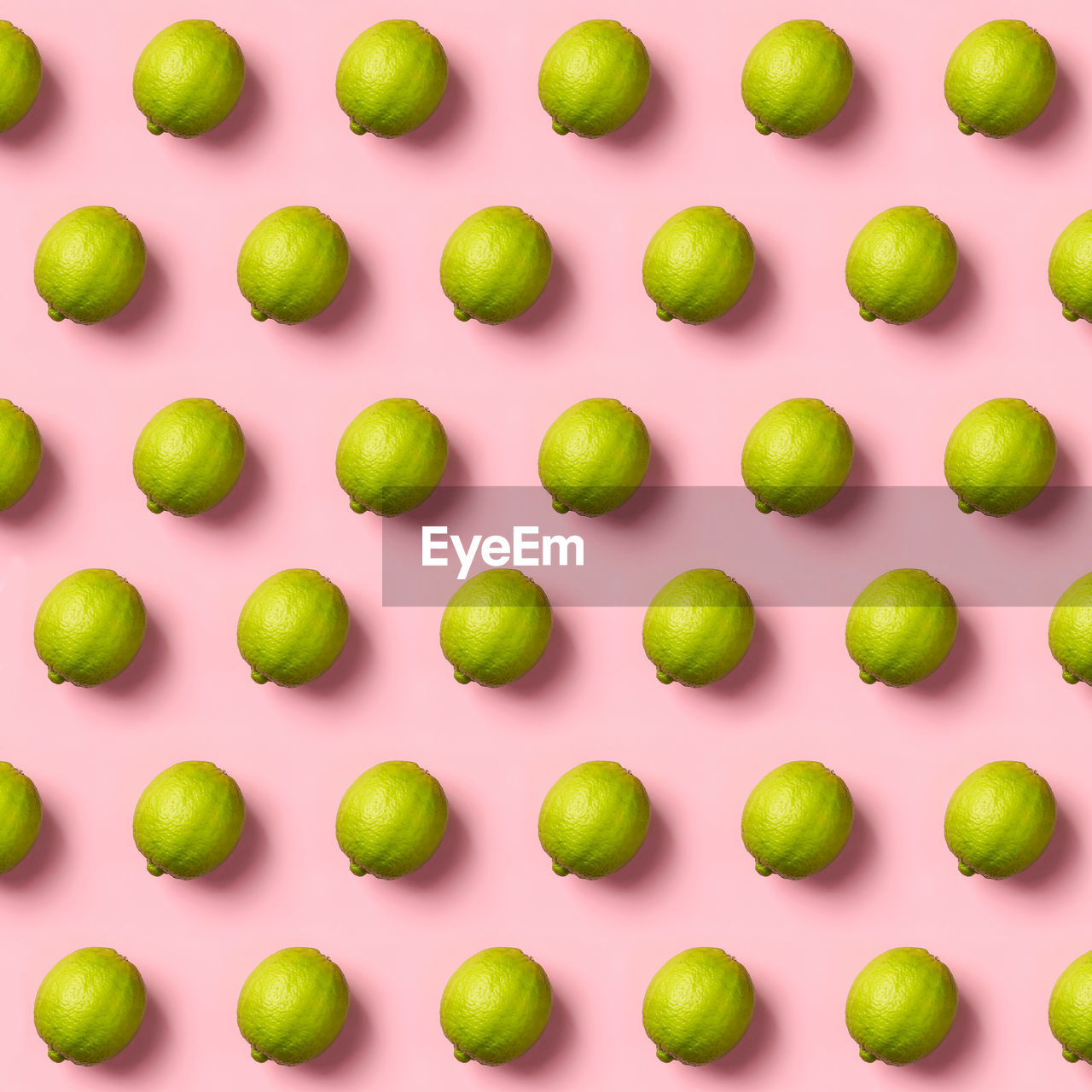 Full frame shot of limes arranged over pink background