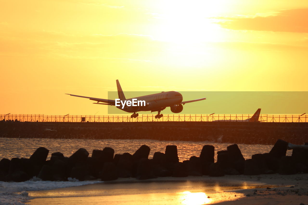 low angle view of airplane on beach against sky during sunset