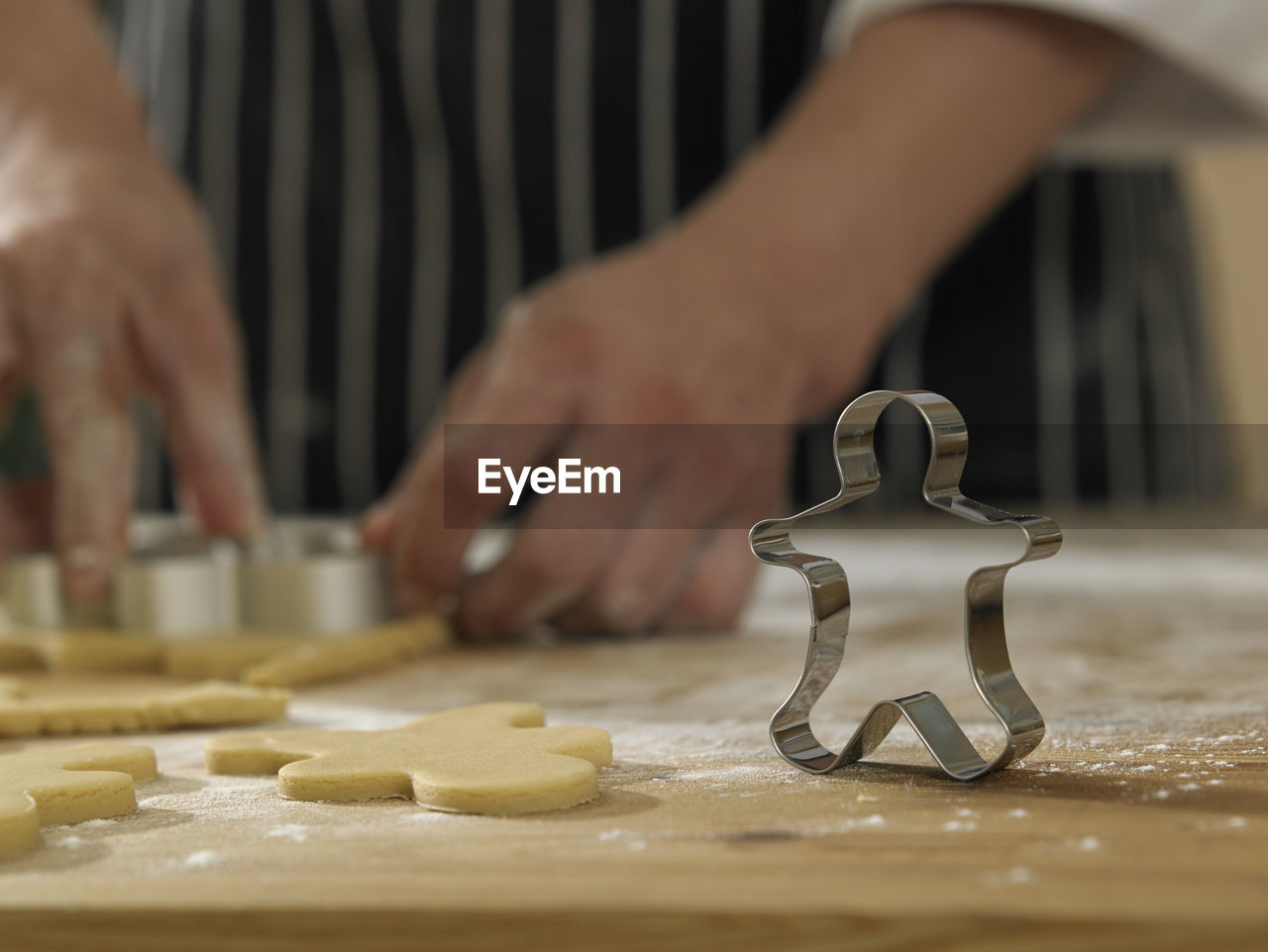 Midsection of chef cutting dough with pastry cutter at table