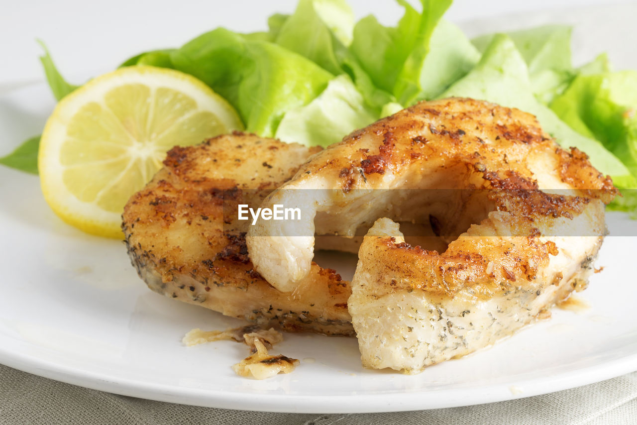 High angle view of seafood with herbs and lemon served in plate on table