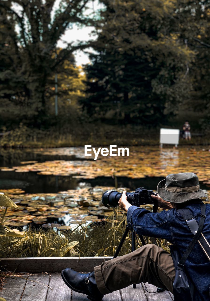 MAN PHOTOGRAPHING PLANTS ON LAND