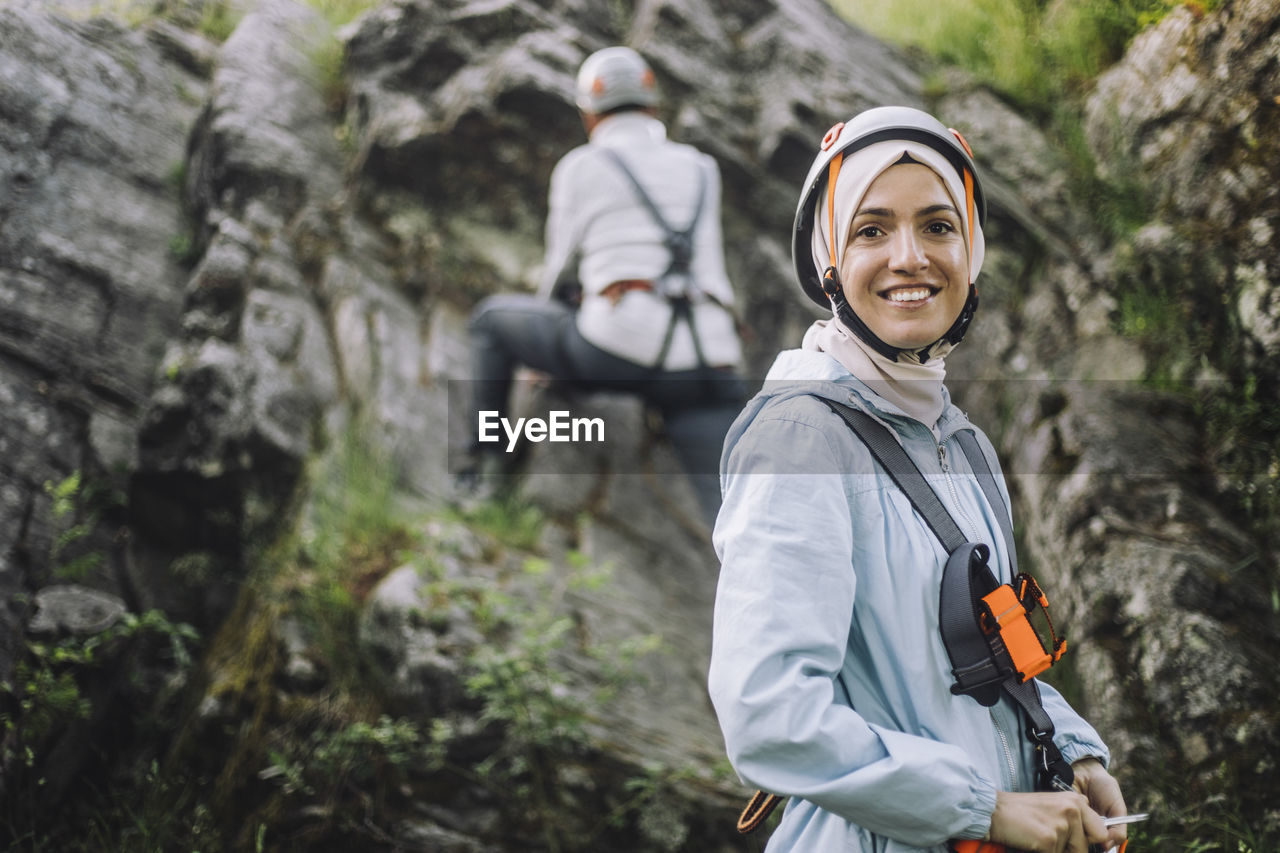 Portrait of smiling woman wearing helmet during rock climbing