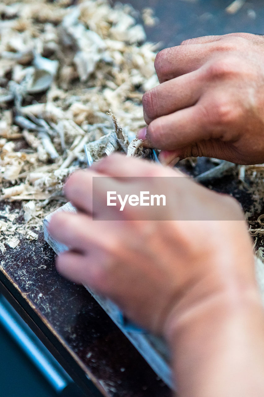 Wood shavings carpenter working with a metal spokeshave and a blurry background.