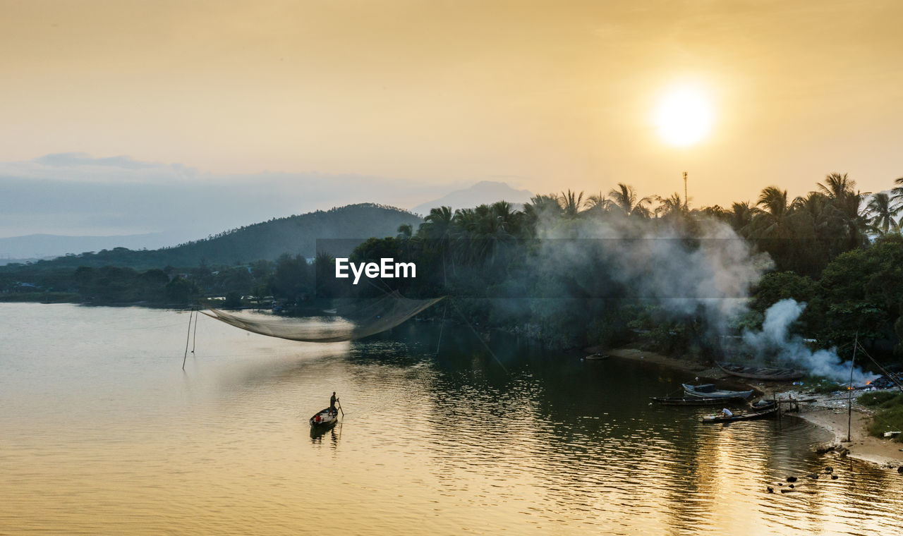 Scenic view of lake by forest against sky during sunset