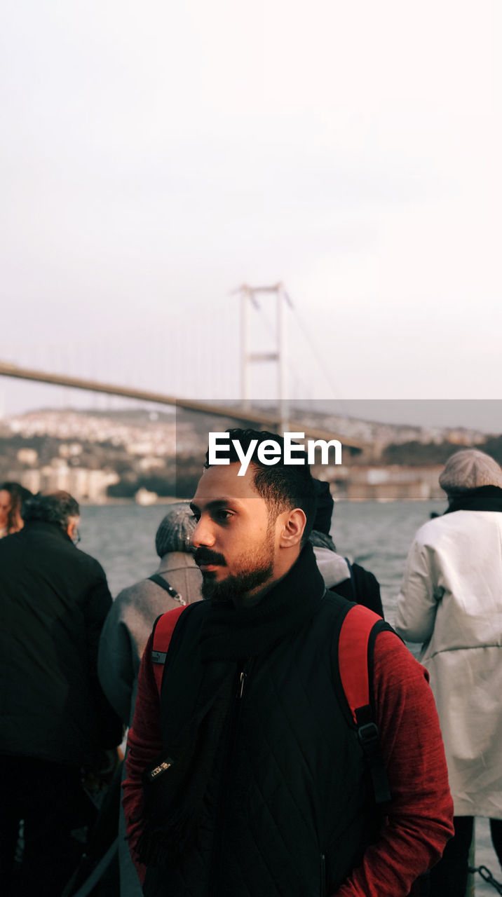 YOUNG MAN STANDING ON SUSPENSION BRIDGE IN WINTER