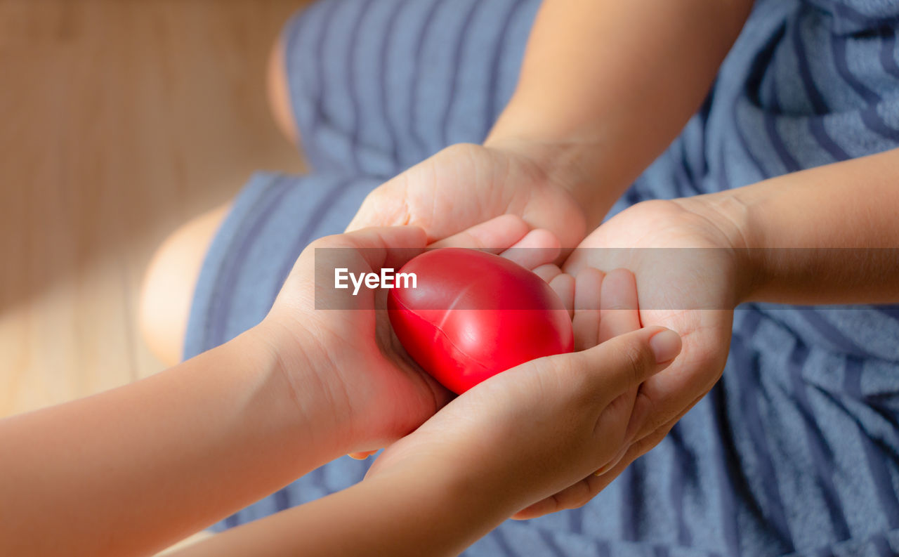 Mother and daughter holding heart shape in home