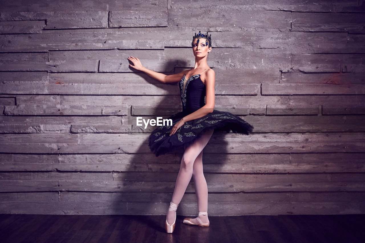 Ballet dancer dancing against wall