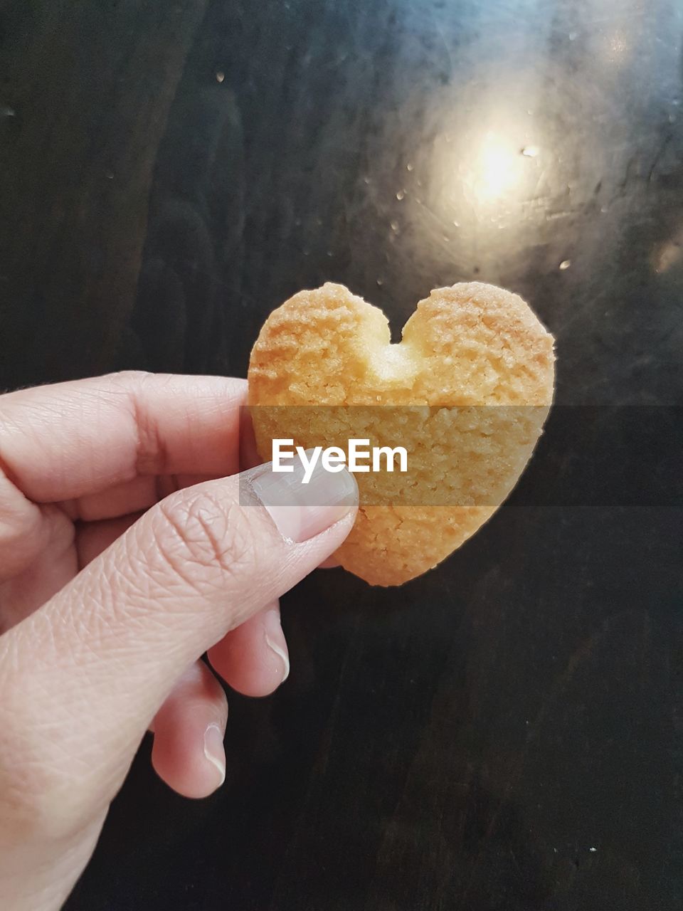 CLOSE-UP OF HAND HOLDING HEART SHAPE MADE OF COOKIES