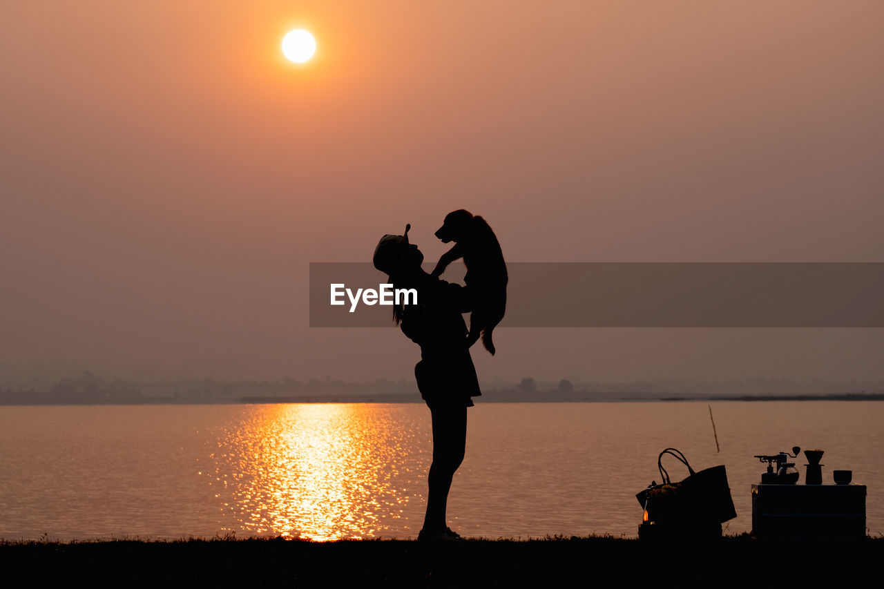 silhouette, water, sunset, sky, sea, nature, horizon, adult, sun, beach, men, beauty in nature, two people, reflection, standing, lifestyles, love, emotion, orange color, sunlight, horizon over water, women, land, positive emotion, leisure activity, tranquility, togetherness, outdoors, scenics - nature, person, back lit, full length, side view, tranquil scene