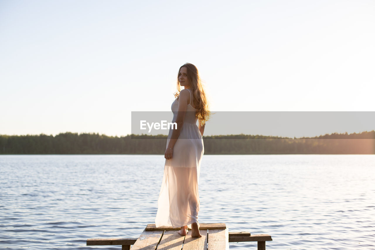Young woman in white dress standing on jetty